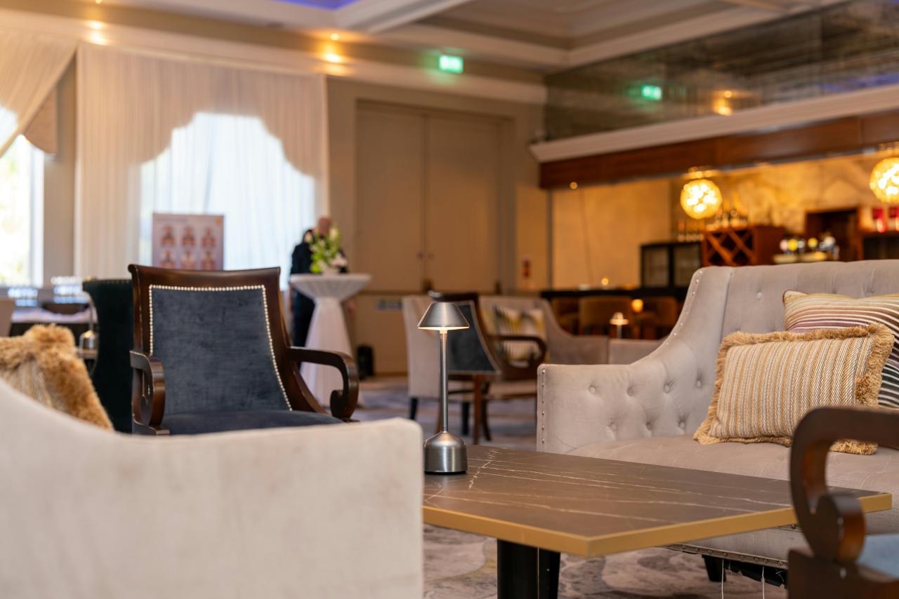 Area lounge yang elegan dengan tempat duduk mewah dan pencahayaan sekitar.